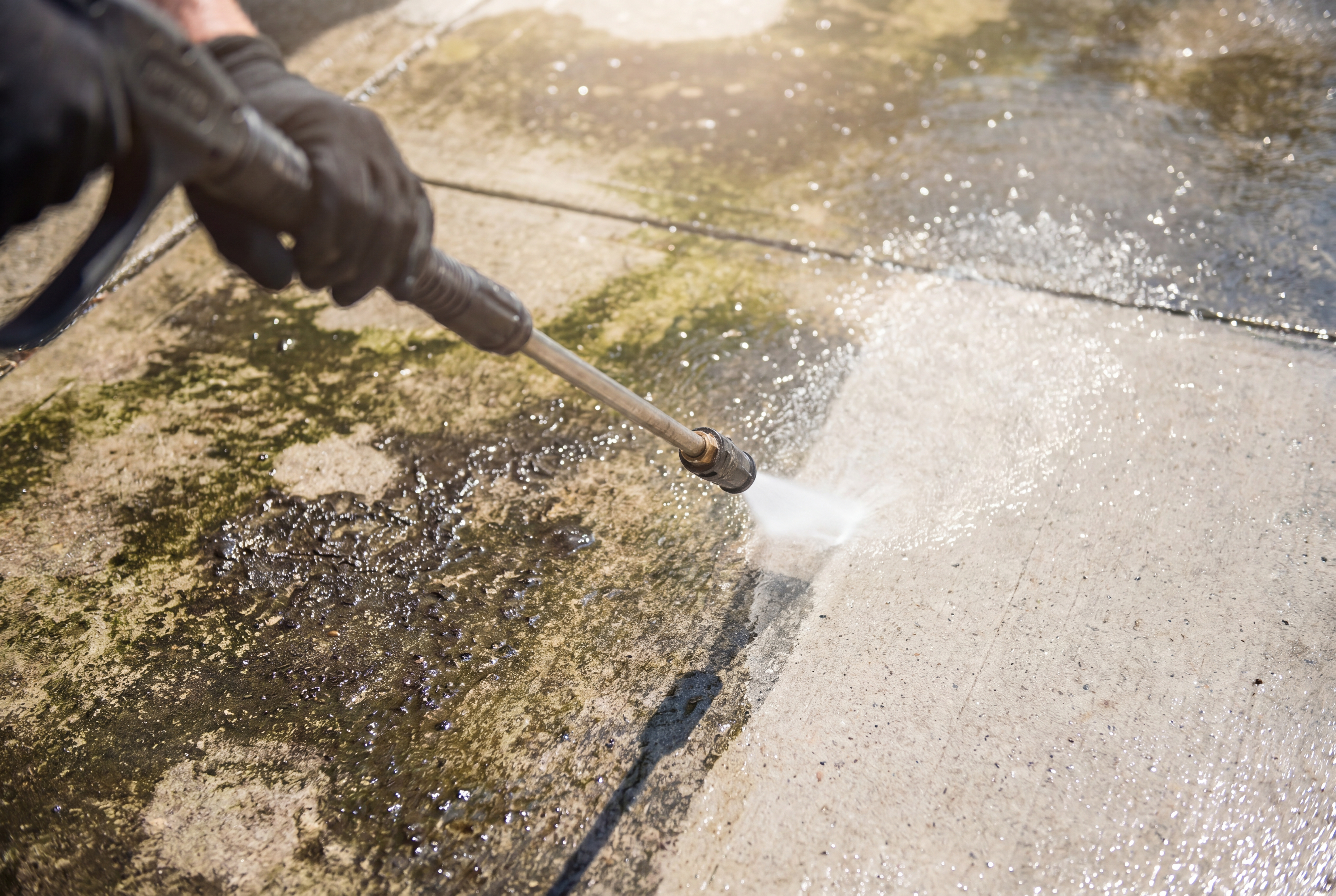 A pressure washer wand cleaning concrete pavers in real time